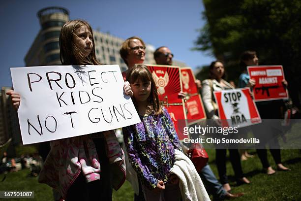 Anti-gun violence demonstrators, including Rachel Ahrens Abby Ahrens and their mother Betty Ahrens hold signs condeming the National Rifle...