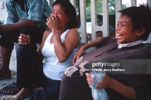 Chhien laughs after he got his "Street Mom" Mao to sniff glue as they sat on a streetside bench. Mao says she occasionally sniffs glue. They are part...