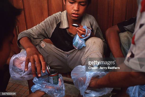 Boys share a can of glue they pooled their money to buy. They will all get high sniffing the glue fumes from plastic bags. They are part of about 20...