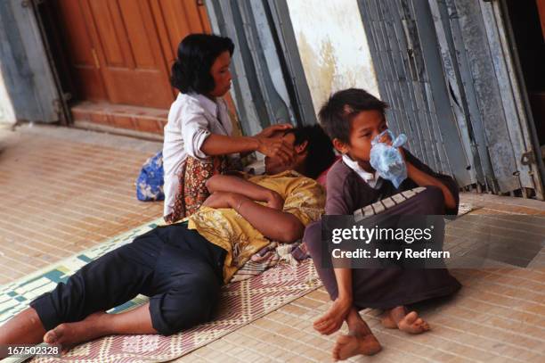 Street Mom" Mao tends to her boyfriend Chhret who passed out after drinking rice wine. Next to them, Chhien huffs a bag of glue while hanging out...