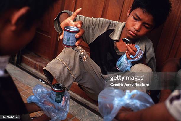 Boys share a can of glue they pooled their money to buy. They will all get high sniffing the glue fumes from plastic bags. They are part of about 20...