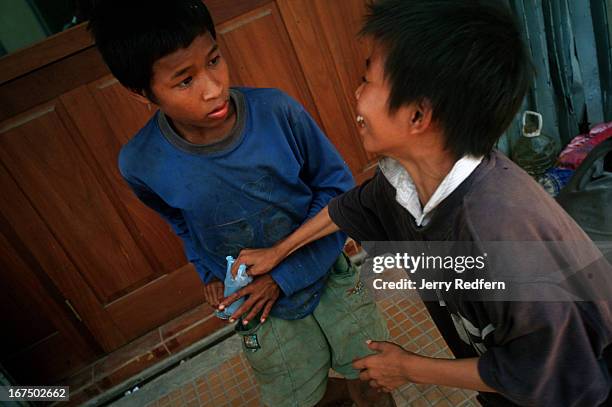 Chhien right, jokingly tries to grab a plastic bag of glue away from Along who is stoned and confused from taking a big hit of glue. They both sniff...