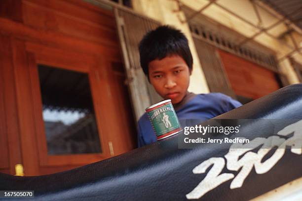 Along stares at his own can of glue. When he has nothing to eat - and often when he does - he sniffs glue. He is part of about 20 kids and adults...