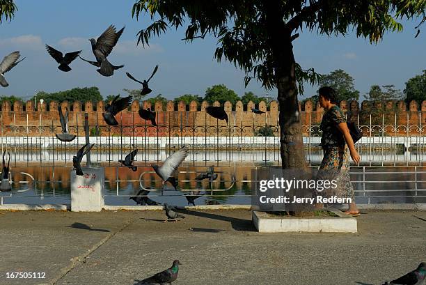 Woman walks around the moat encircling the old royal palace grounds in Mandalay. Today, the grounds are occupied by the military..