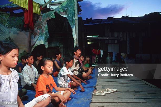 Kids from the Cambodian Light Children Association meditate before practicing a traditional Khmer dance on an open-air stage at the orphanage....