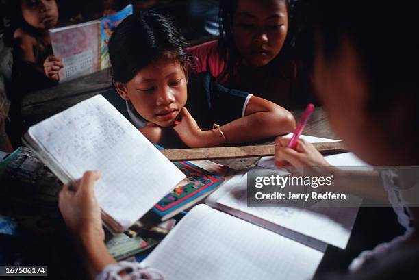 Srei Ong watches as a teacher grades assignments during a class at the Cambodian Light Children Association. The orphanage also teaches kids from the...