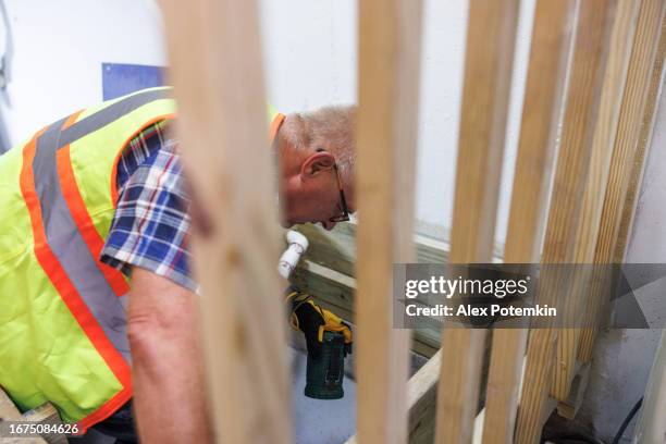 highlight of sump pit with sump pump in basement. mature insurance claim inspector wearing safety vest examine faulty sump pit indoors - sump pump stock pictures, royalty-free photos & images