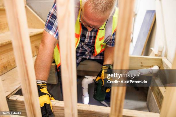 faulty sump pit examining for insurance claim reasons. mature agent checking for cracks, leaks, debris in sump pit drainage system of basement - sump pump stock pictures, royalty-free photos & images