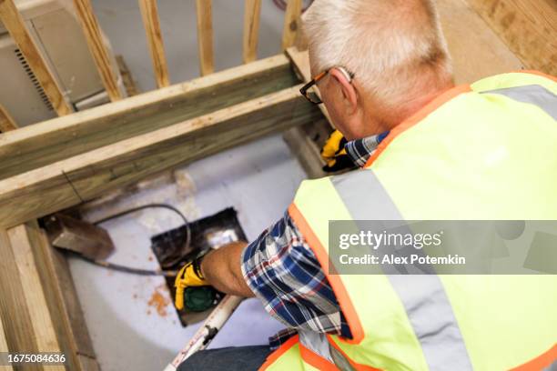 inspection of sump pit drainage system in basement. mature insurance claim inspector checking sump pit drainage system after flood - drainage stock pictures, royalty-free photos & images