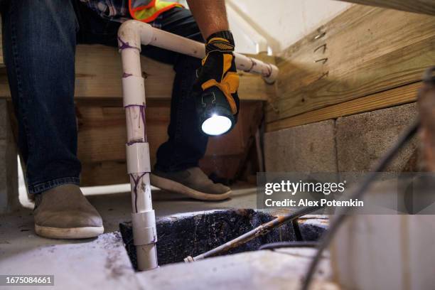 sump pit crash inspection. unrecognizable insurance claim agent's hands with flashlight inspect sump pit pipes, looking for damage - bomba de água equipamento imagens e fotografias de stock