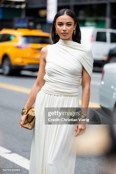 Kelsey Merritt wears white wrapped dress, beige bag outside Altuzarra on September 11, 2023 in New York City.