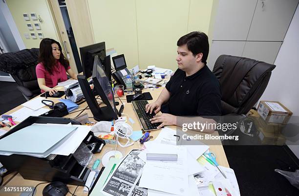 Mark Karpeles, chief executive officer of Tibanne Co., right, works at his desk in the office operating the Mt.Gox K.K. Bitcoin exchange in Tokyo,...