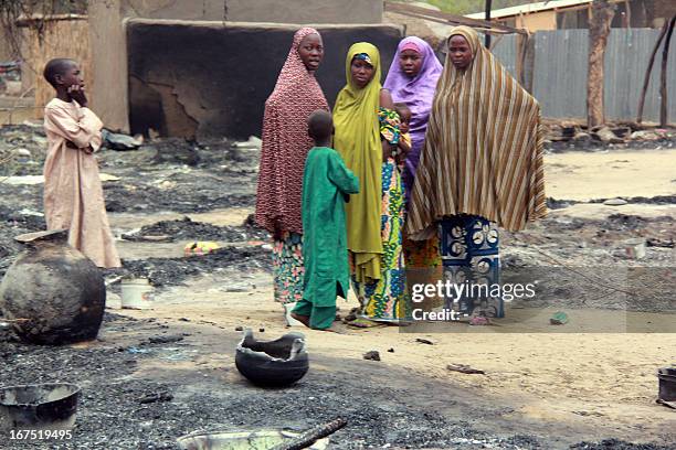 Women and children stand in front of burnt houses in the remote northeast town of Baga on April 21, 2013 after two days of clashes between officers...