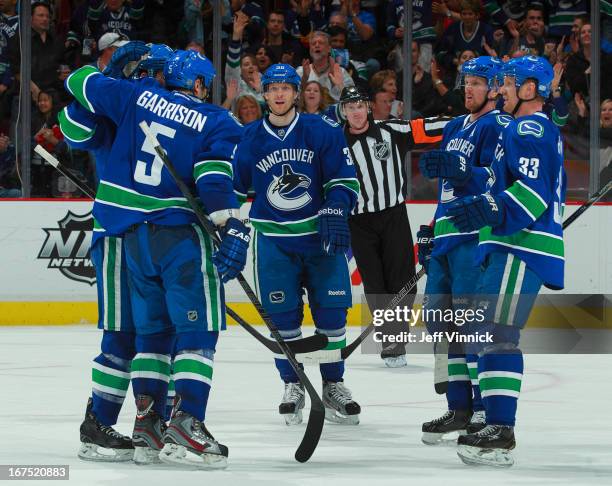 Jason Garrison of the Vancouver Canucks is congratulated by teammates Daniel Sedin, Henrik Sedin and Jannik Hansen after scoring against the Anaheim...