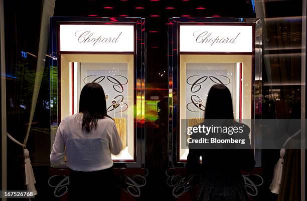 Visitors look at a display of wristwatches manufactured by Chopard & Cie SA at the company's booth during the Baselworld watch fair in Basel,...