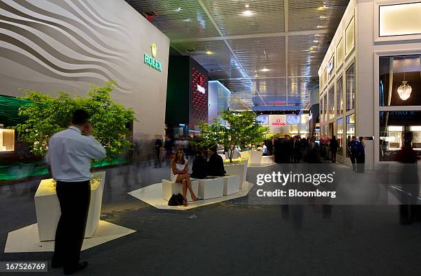 Visitors walk past display halls for Rolex Group, Tudor, and Omega watches during the Baselworld watch fair in Basel, Switzerland, on Thursday, April...
