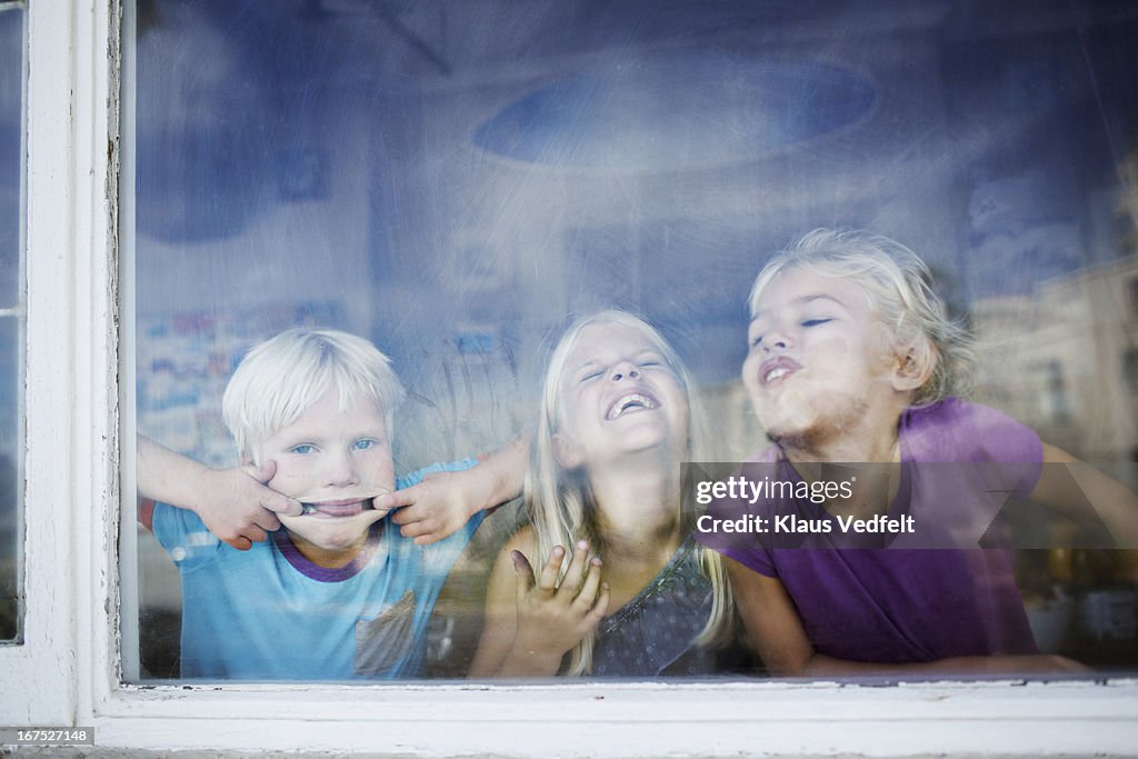 Children making funny faces behind windows