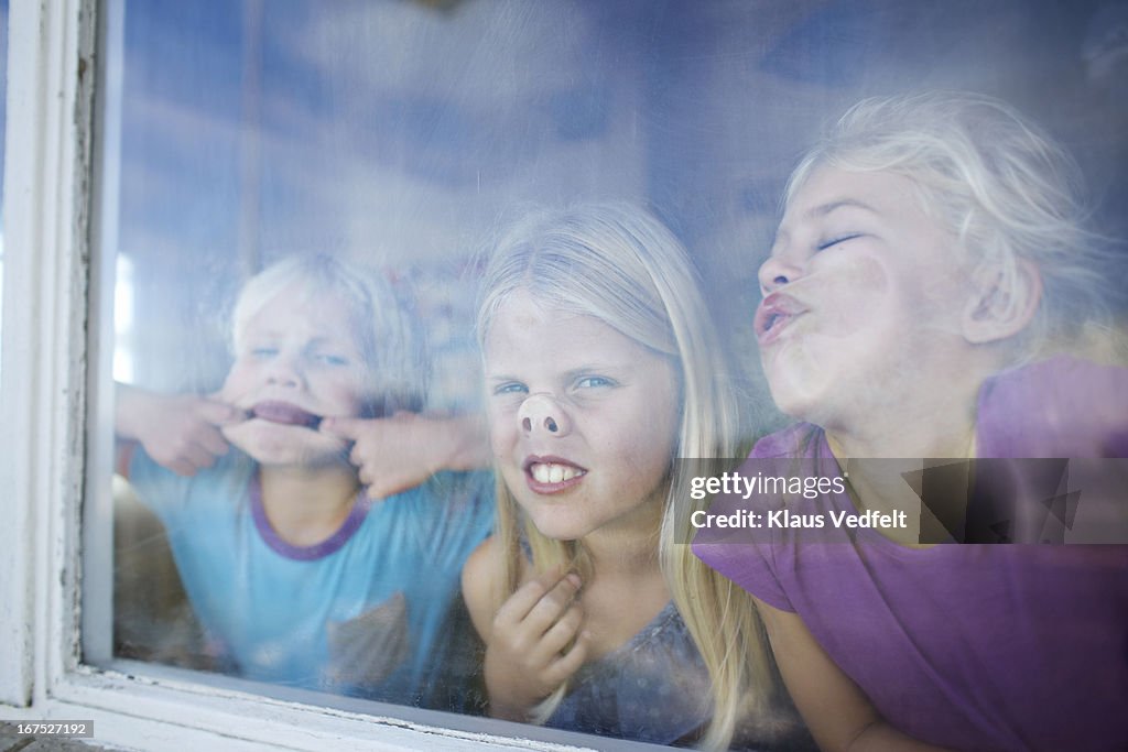 Kids making funny faces behind window