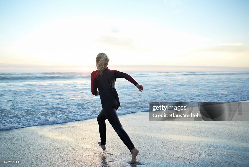 Girl running towards ocean in sunset
