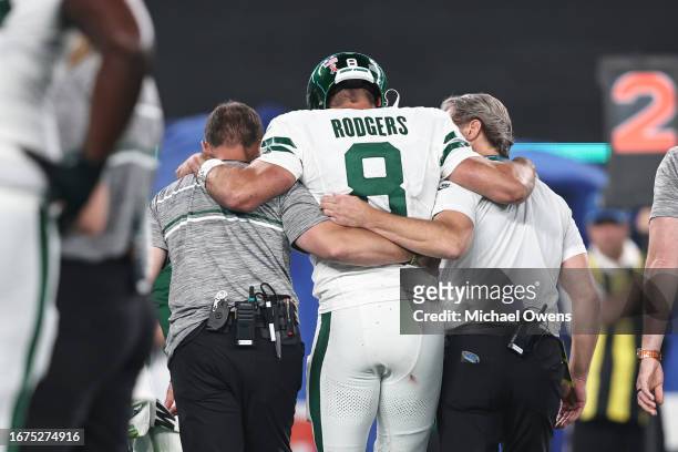 Aaron Rodgers of the New York Jets is helped off the field after suffering an apparent injury after being sacked by Leonard Floyd of the Buffalo...