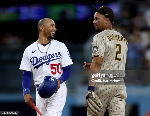 Mookie Betts of the Los Angeles Dodgers and Xander Bogaerts of the San Diego Padres laugh at second base during after a stop in play during the third...
