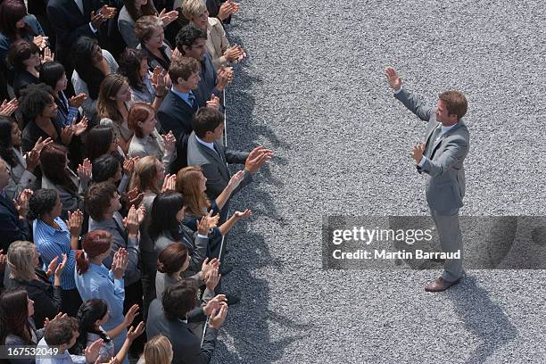 businessman addressing clapping crowd - young men talking stock pictures, royalty-free photos & images