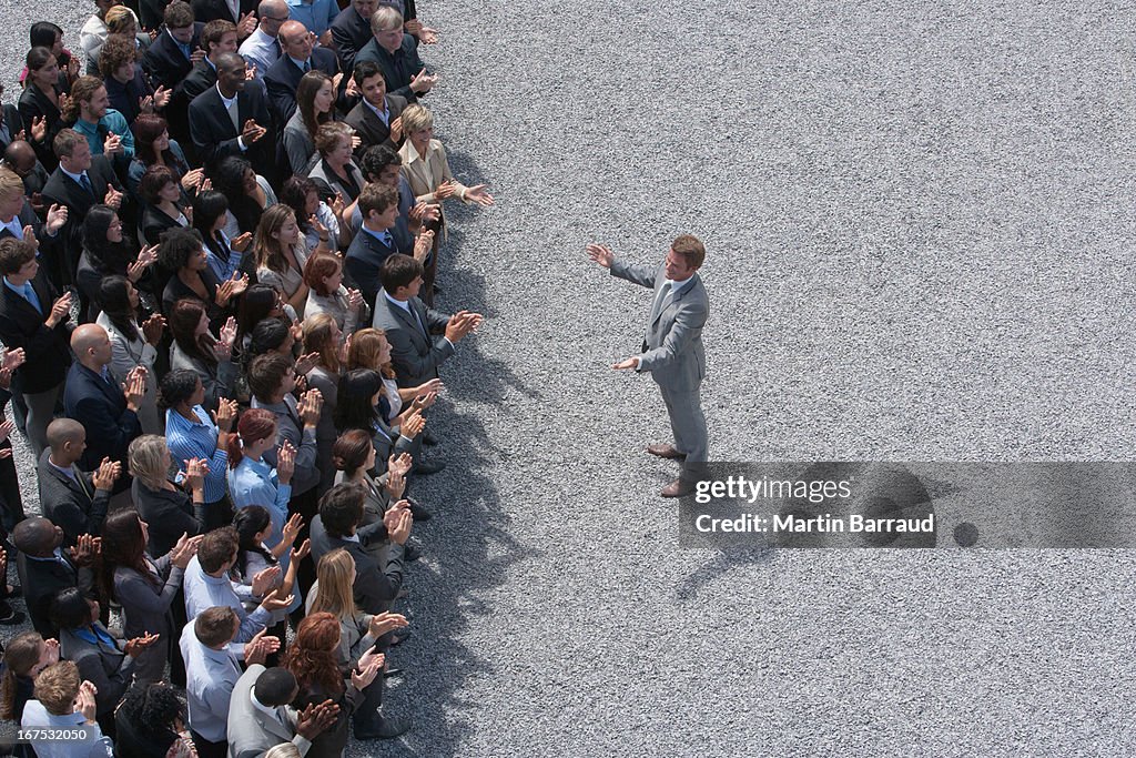 Businessman addressing clapping crowd
