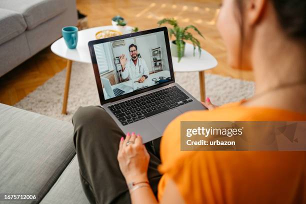 young woman having a doctor's appointment online at home - online doctor stock pictures, royalty-free photos & images