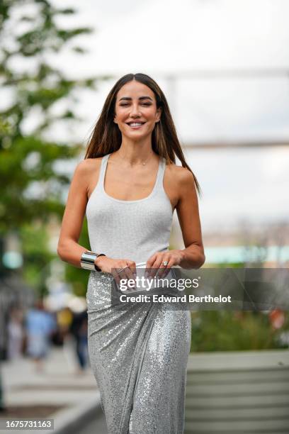 Tamara Kalinic wears a gray tank top, a gray / silver shiny glitter maxi slit skirt, silver high heel shoes, outside Michael Kors, during New York...