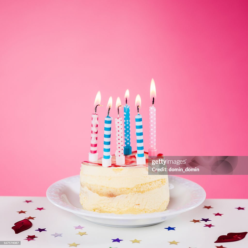 Geburtstagstorte mit Kerzen auf dem Tisch, Rosa Hintergrund