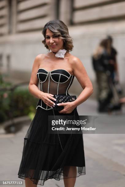 Olga Ferrara is seen wearing white cotton flower neck detail, a see through black Munique corset with white stitching, a black ruffled JNBY midi...