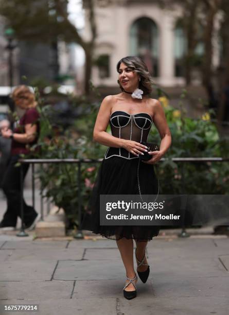 Olga Ferrara is seen wearing white cotton flower neck detail, a see through black Munique corset with white stitching, a black ruffled JNBY midi...