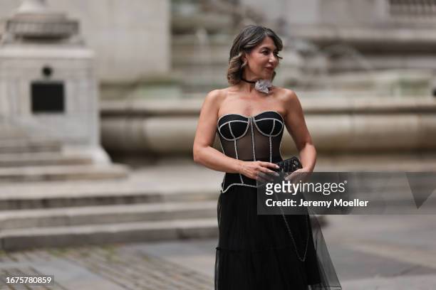 Olga Ferrara is seen wearing white cotton flower neck detail, a see through black Munique corset with white stitching, a black ruffled JNBY midi...