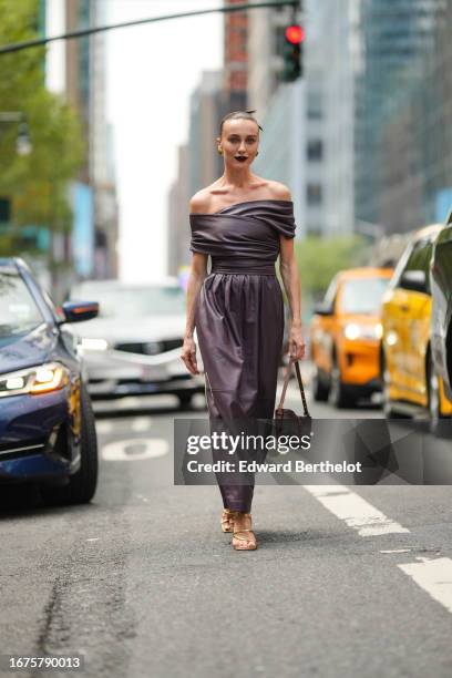 Mary Leest wears purple gathered leather off-shoulder leather dress, a bag, earrings, outside Altuzarra, during New York Fashion Week, on September...