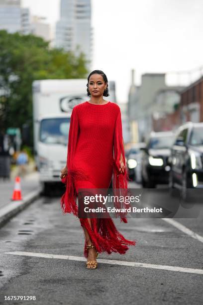 Sai De Silva wears a red wool long pullover worn as a dress with attached long fringes, outside Michael Kors, during New York Fashion Week, on...