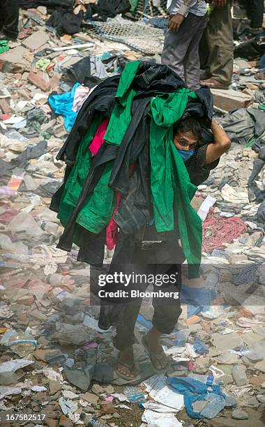 Man removes clothing bearing a label that reads 'Joe Fresh' from around the devastated area of the collapsed Rana Plaza building in Dhaka,...