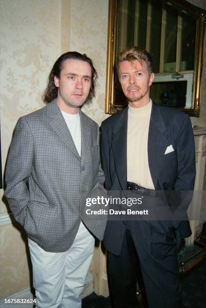 English singer David Bowie with English artist Damien Hirst at Bowie's first solo art exhibition 'New Afro-Pagan and Work 1975-1995' at The Gallery...