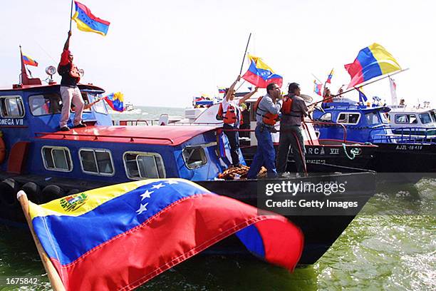 Striking oil workers hold Venezuelan flags as they head out on a boats to show their support for crewmembers on strike on oil tankers December 6,...