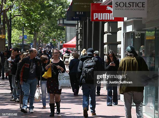 Pedestrians carry shopping bags as they walk along Market Street on April 26, 2013 in San Francisco, California. The Commerce Department reported...