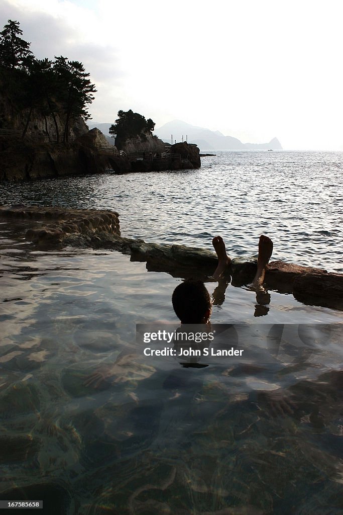 Bather looks out at the Pacific from an open-air hot spring...