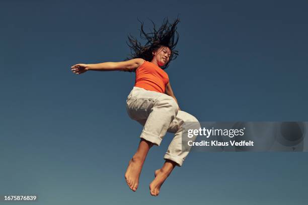 young woman with tousled hair jumping mid-air - barefoot gymnastics stock pictures, royalty-free photos & images