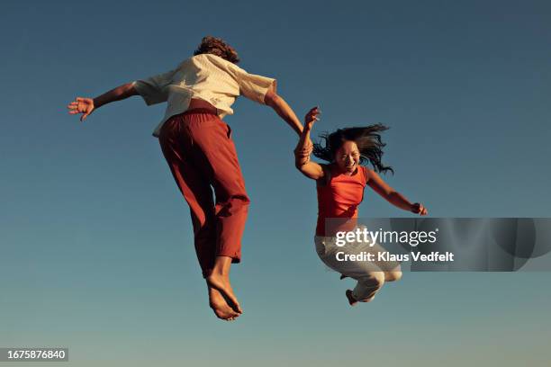 happy friends jumping high up in mid-air - levitation stock-fotos und bilder