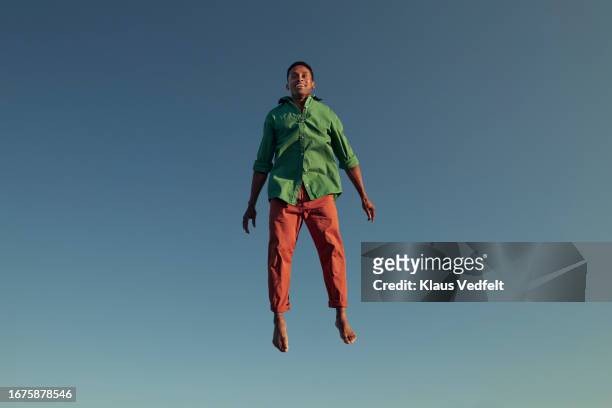 happy man levitating against clear blue sky - barefoot black men stock pictures, royalty-free photos & images