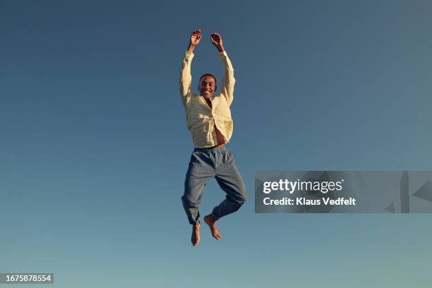 happy young man jumping high with arms raised - perspektivenwechsel stock-fotos und bilder
