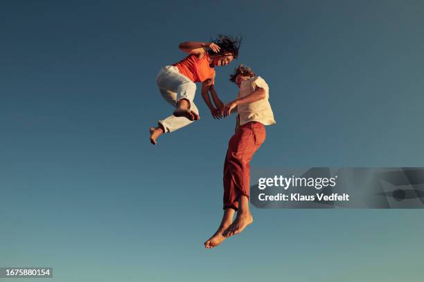 cheerful friends jumping high up in mid-air - exhilaration stockfoto's en -beelden