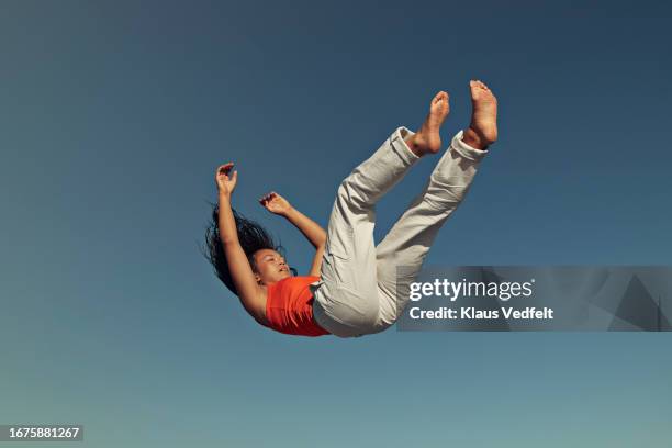 side view of young woman falling against clear blue sky - up in the air stock pictures, royalty-free photos & images