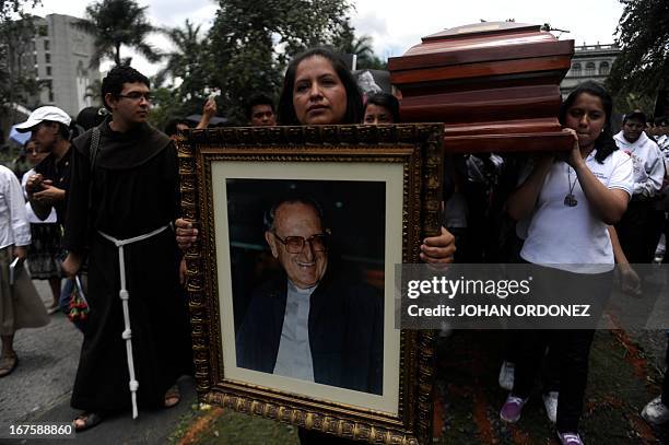 Woman holds a picture of Monsignor Juan Jose Gerardi as the coffin with his remains is moved to a new crypt within the Metropolitan Cathedral, during...