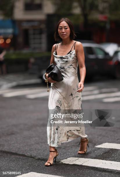 Aimee Song is seen wearing golden hoop earrings, a sleeveless maxi dress with floral print in beige satin from Jason Wu, a black leather bag from...
