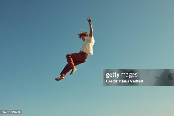 full length view of young man jumping high in mid-air - 幸運 ストックフォトと画像