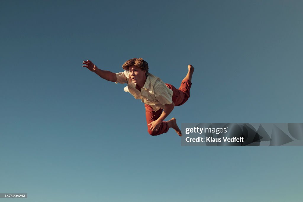 Young man with hand raised flying in mid-air